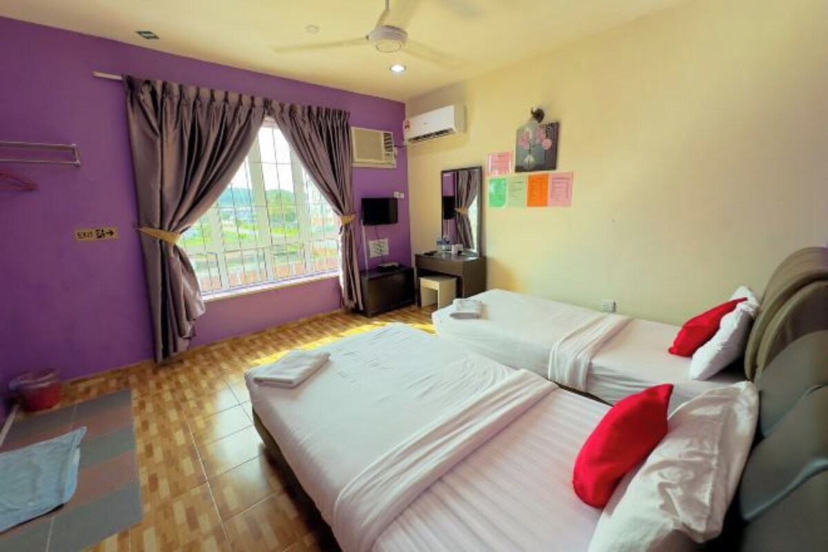 Habitación de hotel con dos camas, un escritorio, aire acondicionado, ventilador de techo y una ventana con cortinas.
