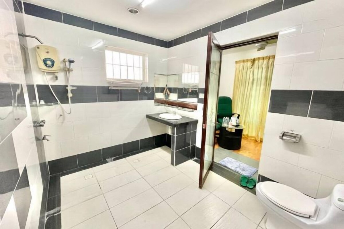 A bathroom with a shower, toilet, sink, and mirror.