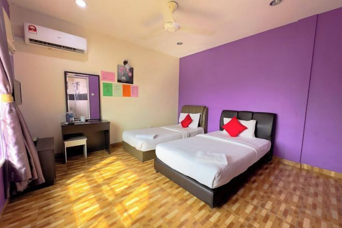 A hotel room with two beds, a desk, a chair, and a ceiling fan.