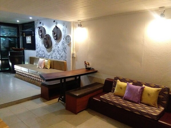 Una sala de estar con un sofá, un banco, una mesa de comedor y una pared decorada con relojes.