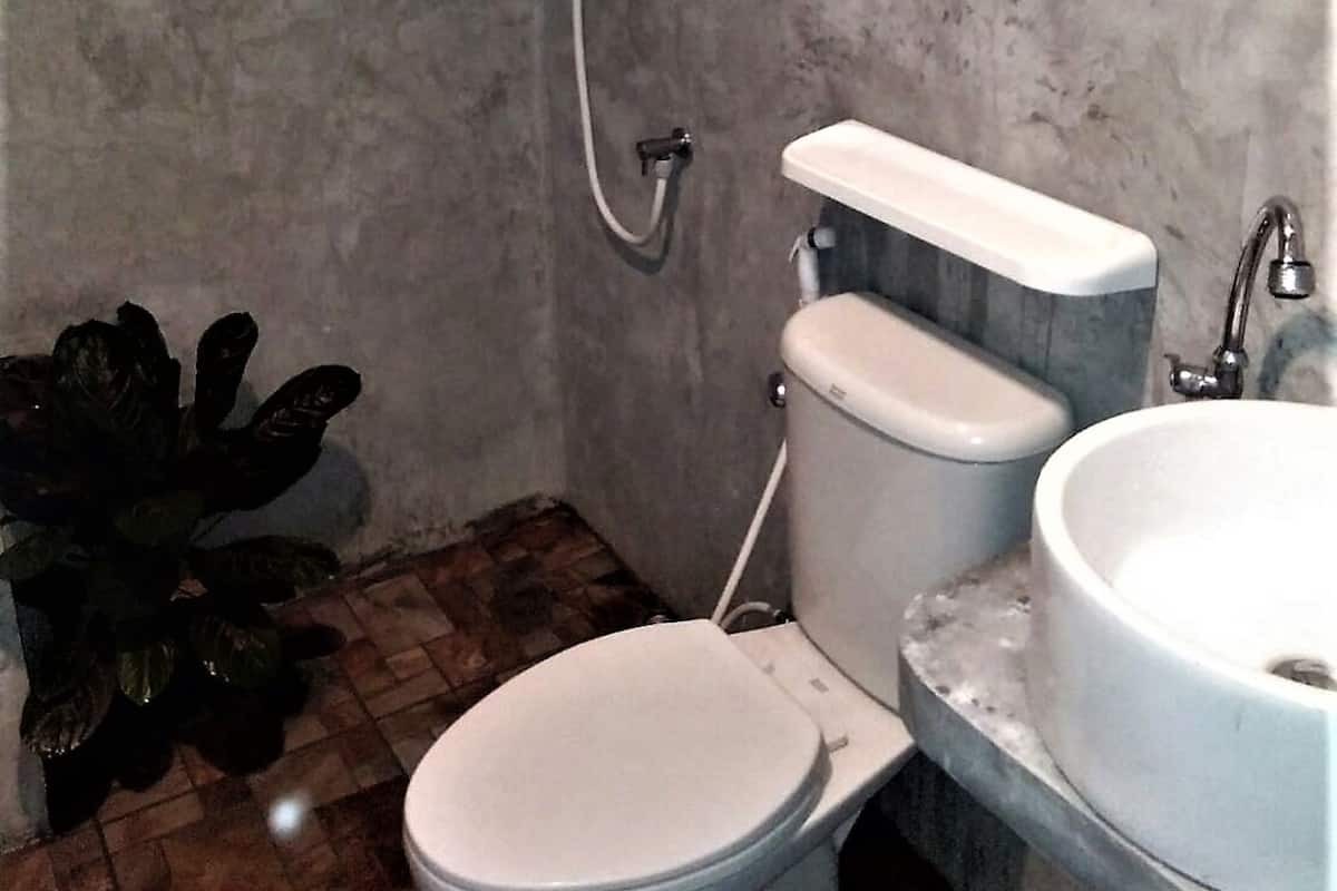 Een compacte badkamer met toilet, hygiëneschuimer en wastafel.