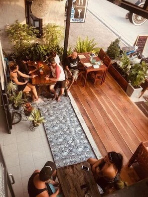 Un espacio al aire libre con mesas y sillas, rodeado de plantas en macetas.