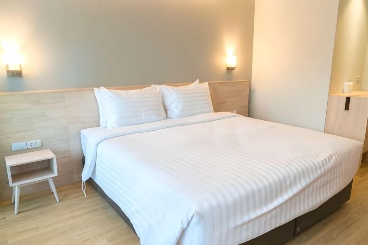 Una habitación de hotel con una cama grande, mesitas de noche e iluminación en la pared.