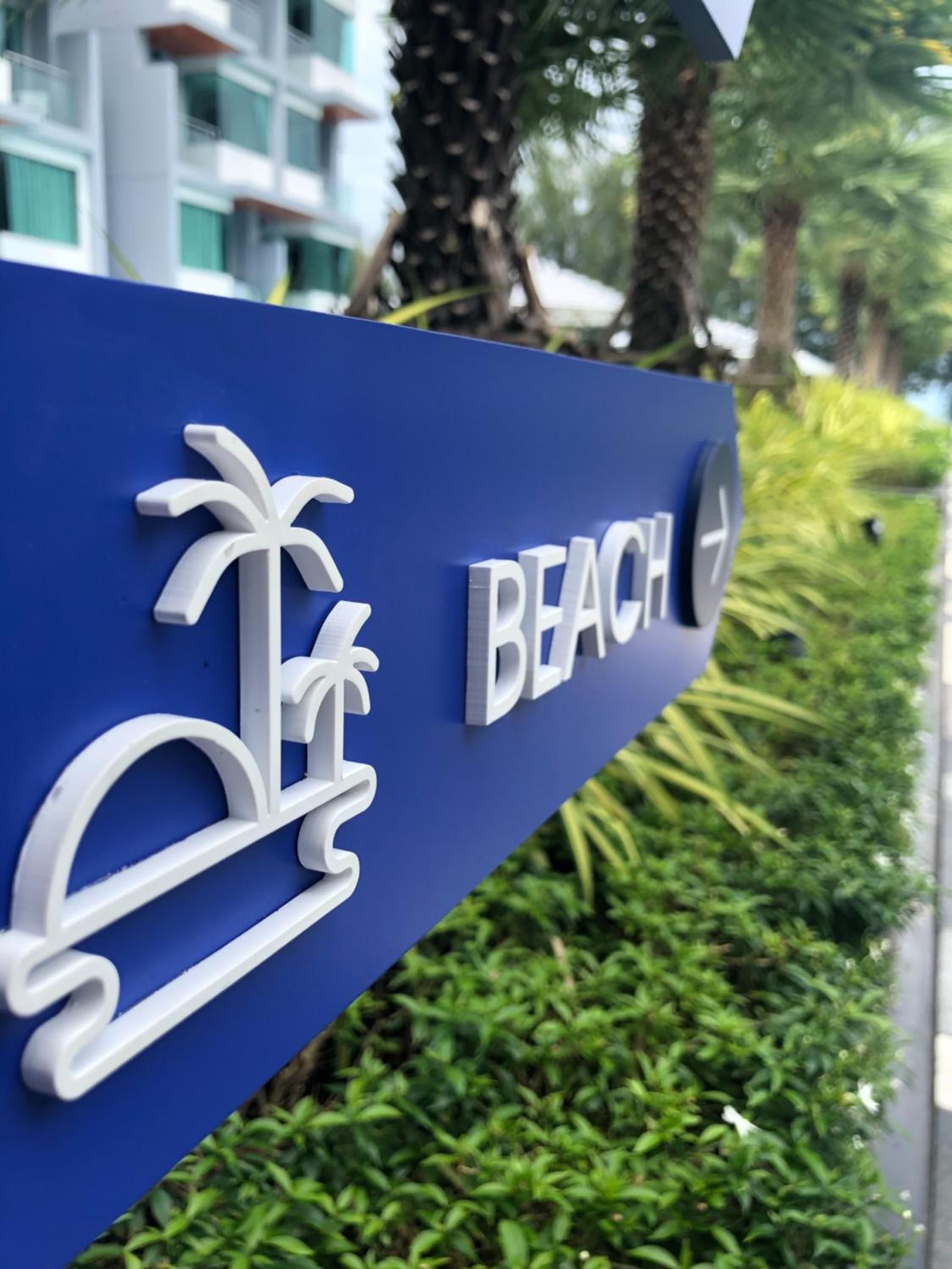 A blue sign with the word 'BEACH' and a palm tree symbol, indicating a beachfront location.