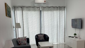 A modern living room with a sofa, armchair, coffee table, TV, and a ceiling fan. - Almyra Serviced Residence (Kajang)