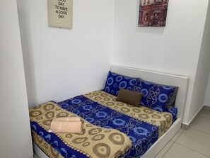 A neatly made bed with patterned bedding, a wall-mounted sign, and a framed picture. - Almyra Serviced Residence (Kajang)