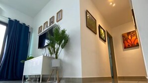 A modern living room with a white cabinet, a flat-screen TV, and a potted plant. - Almyra Serviced Residence (Kajang)