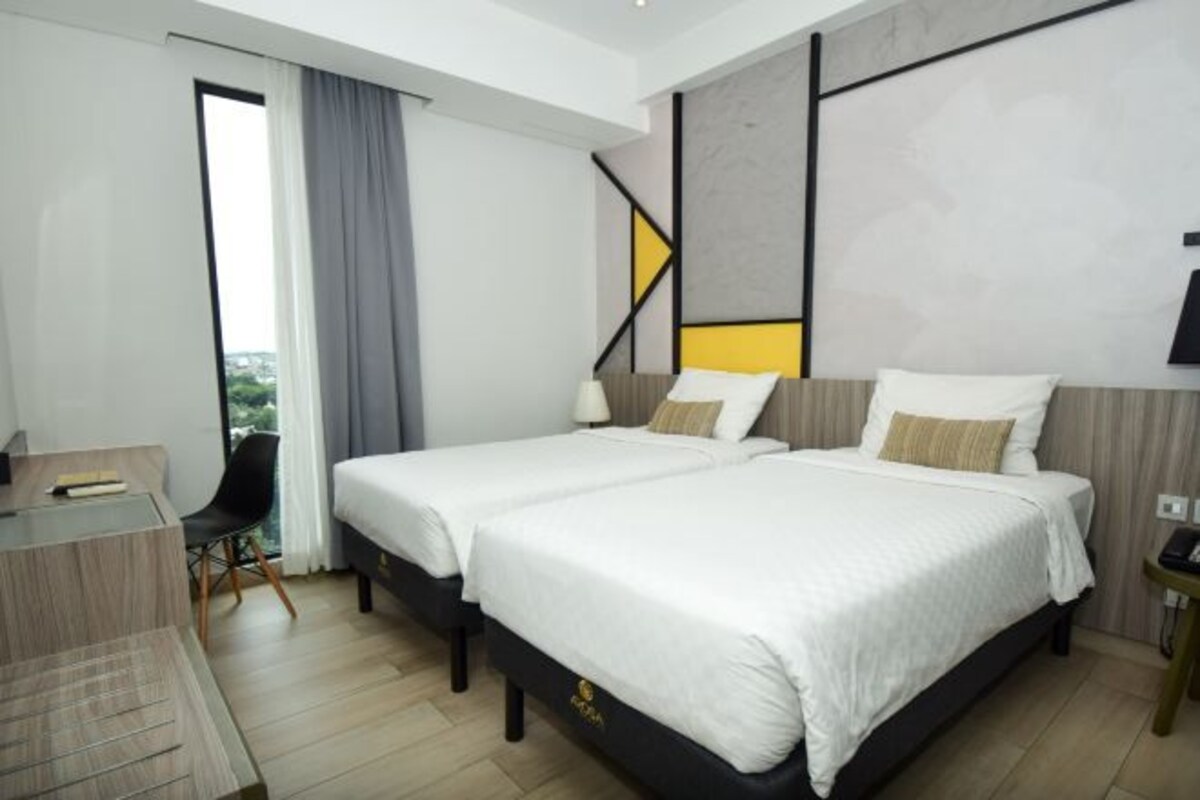 Una habitación de hotel moderna con dos camas, un escritorio y una silla.