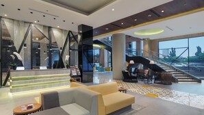 Un hall d’entrée spacieux, doté d’un escalier moderne, de coins salon et d’un comptoir d’accueil.