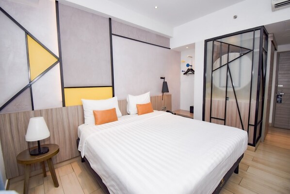 A modern hotel room with a large bed, a bedside table with a lamp, a wardrobe, and a glass partition. - Arosa Hotel Jakarta (Jakarta)