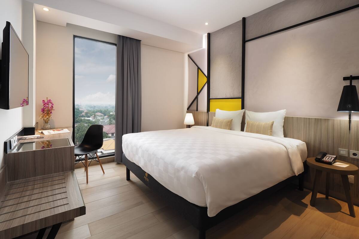 Ein modernes Hotelzimmer mit einem großen Bett, einem Schreibtisch und einem Sessel.