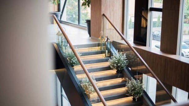 Un escalier moderne avec des marches en bois et des rampes en métal, menant à l’étage supérieur.