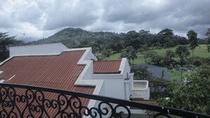 A building with a red roof and white walls, surrounded by lush greenery and hills. - Les Flamants Rose - Gulfview (Yaoundé)
