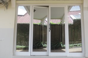A set of white sliding glass doors leading to a covered outdoor area with a tiled floor and potted plants.
