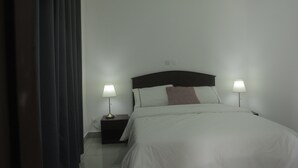 A neatly made bed with white linens, two bedside lamps, and a dark headboard. - Les Flamants Rose - Gulfview (Yaoundé)