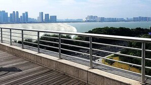 A cityscape with a river, modern buildings, and a pedestrian walkway with a metal railing. - Hangzhou Tianyuan Tower Hotel (Hangzhou)