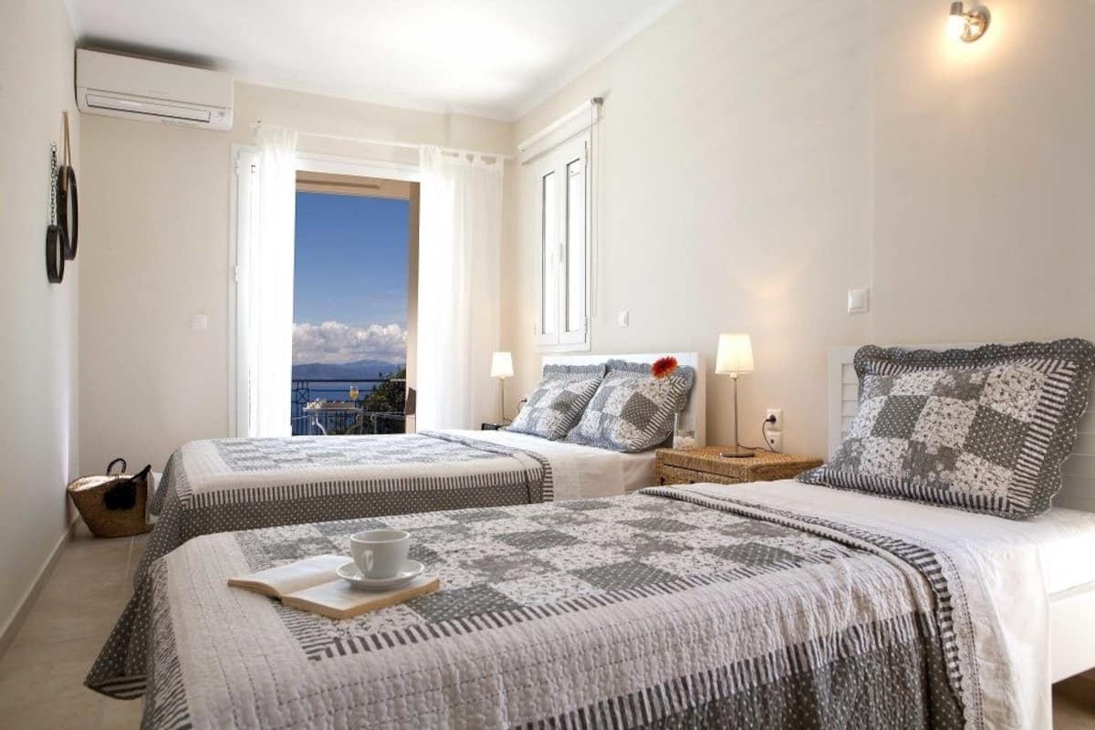 Une chambre d’hôtel avec deux lits, une vue sur la mer et un balcon.