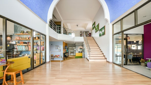 A spacious atrium with a wooden floor, a staircase, and a view of a store on the left. - OYO 145 Pattaya Bed Boutique (Pattaya)
