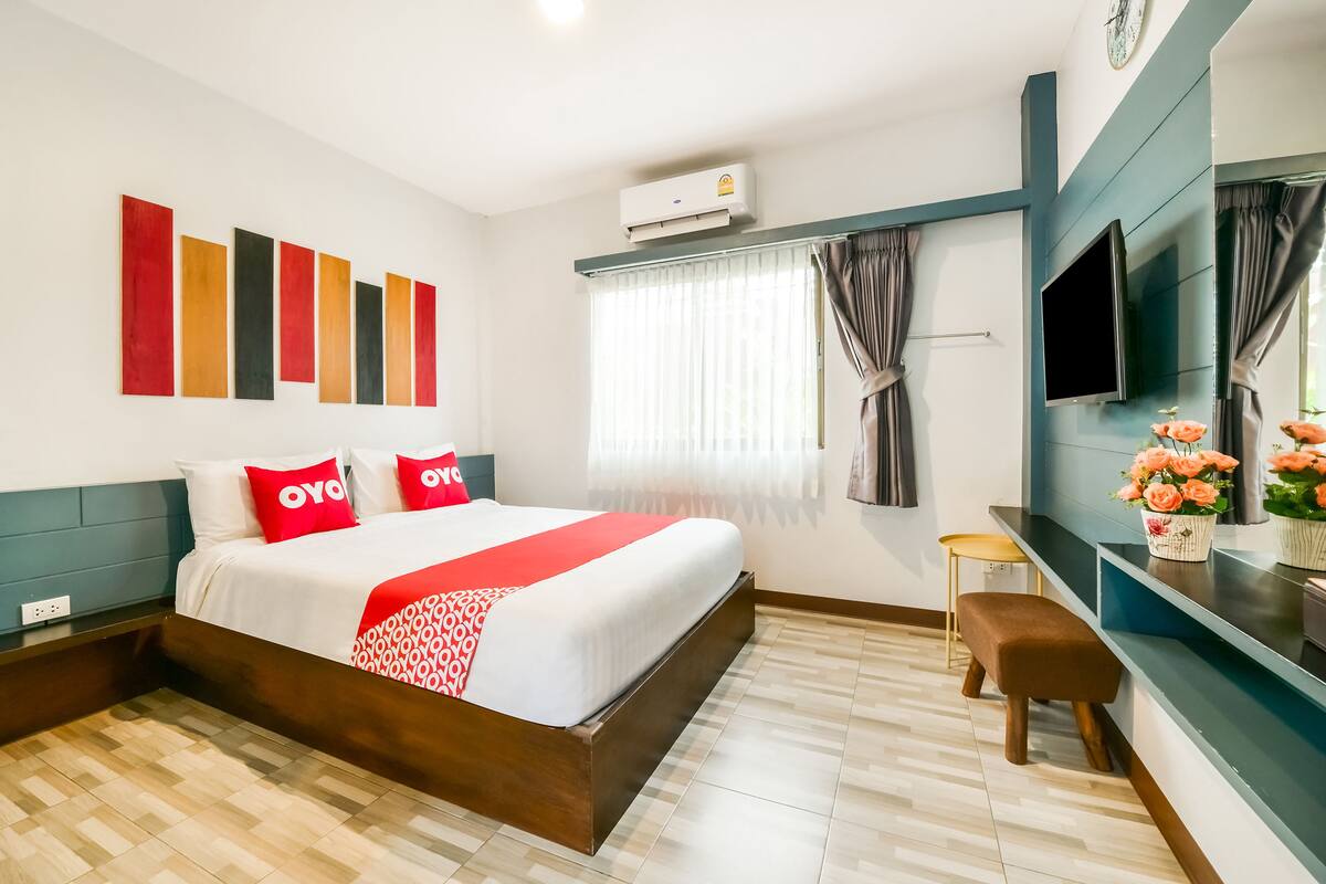 Une chambre d’hôtel avec un grand lit, une télévision, une petite table et une fenêtre avec des rideaux.