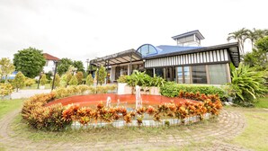 A modern building with a covered entrance, a landscaped garden with a circular water feature, and a variety of plants. - OYO 145 Pattaya Bed Boutique (Pattaya)