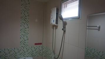 Un baño con inodoro, ducha con cabezal de ducha manual y ventana.