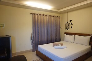 A neatly made bed with white linens, a wooden headboard, and a small bedside table with a lamp. - Sabaidee Resort Satun (Satun)