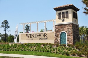 A sign for 'Windsor at Westwood' with a stone and white structure, a pergola, and landscaped greenery.