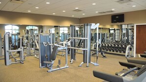 A gym with various exercise machines, mirrors, and weight racks.