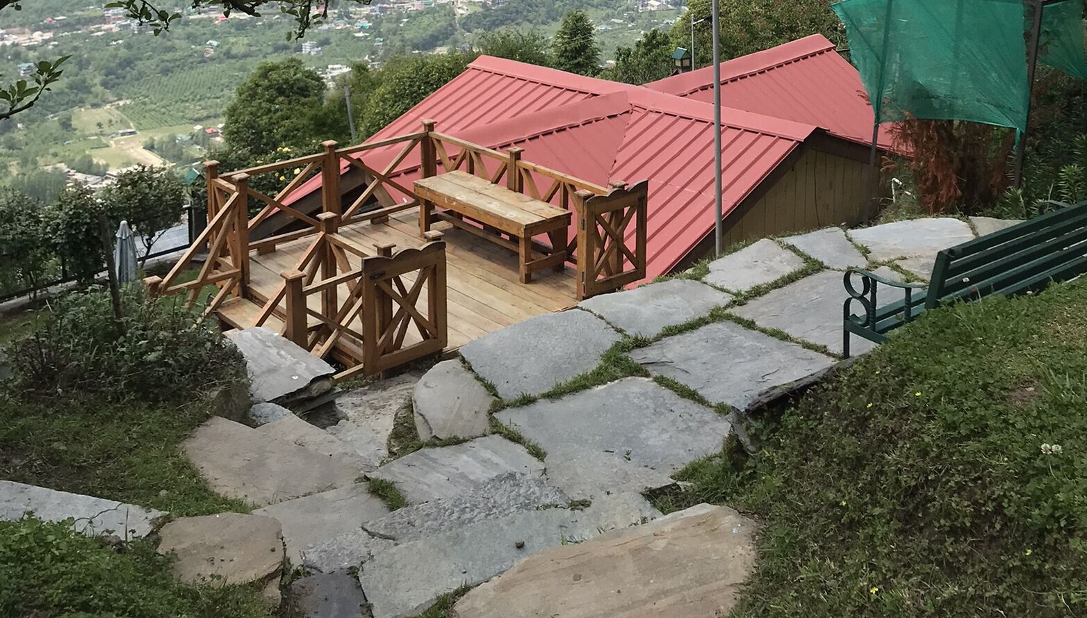A wooden deck with a red roof, stone steps, and a bench.