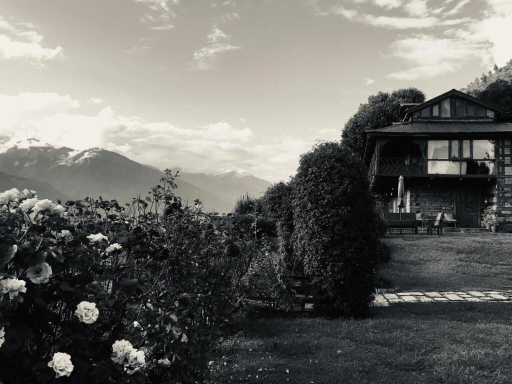 Un edificio con un giardino e montagne sullo sfondo.