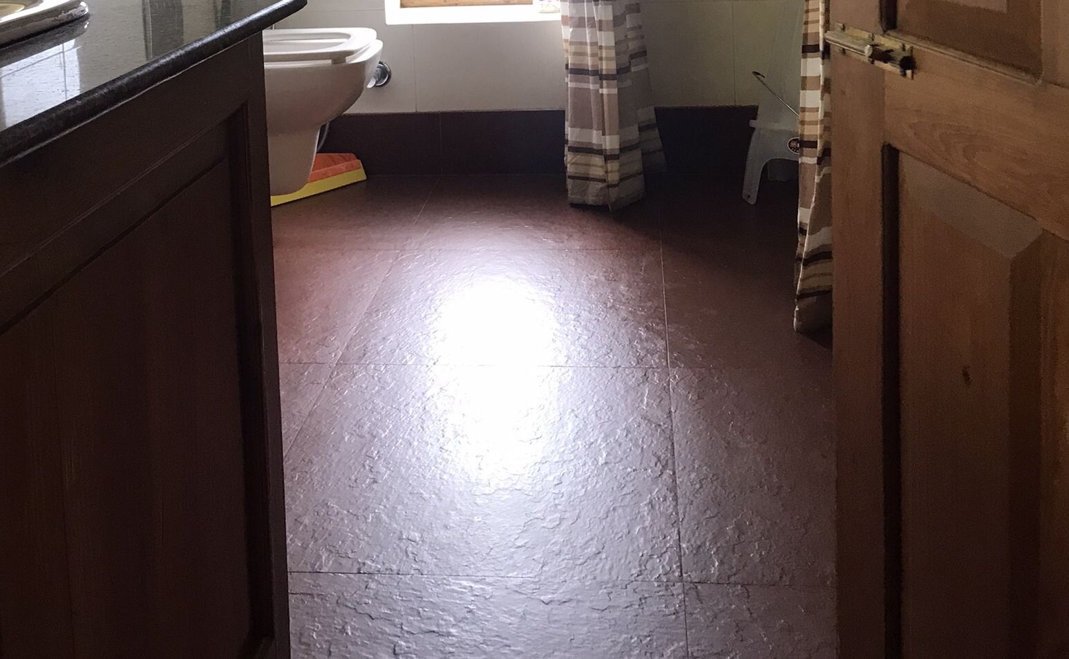 A bathroom with a toilet, a shower area, and a wooden cabinet.
