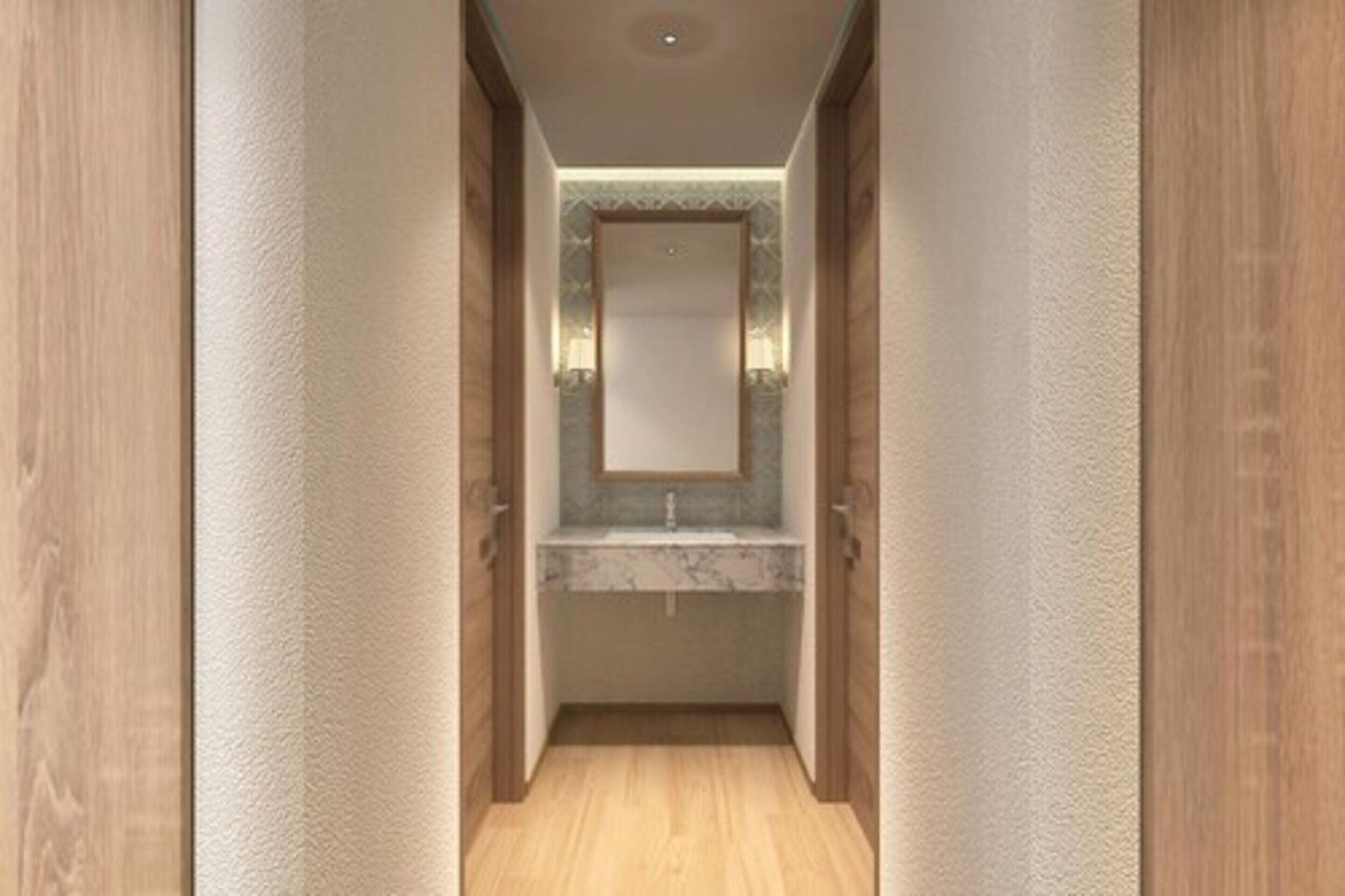 Un pasillo estrecho con suelo de madera y paredes, que conduce a un baño con lavamanos de mármol y un espejo encima.