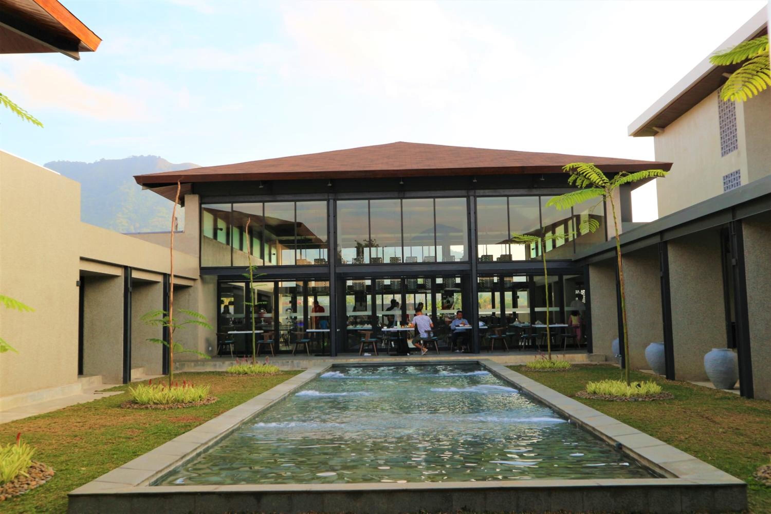 A modern outdoor dining area with a central water feature, surrounded by seating and glass walls.