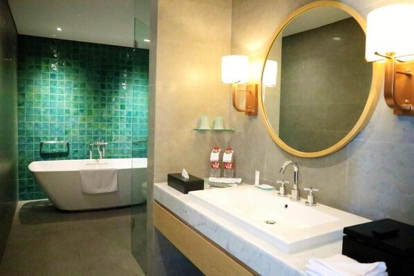 Un baño moderno con una bañera independiente, un espejo grande y un tocador con lavamanos.