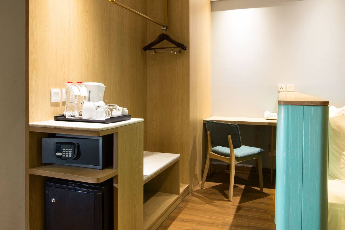 Ein kleines Hotelzimmer mit Küchenzeile, Schreibtisch, Stuhl und Bett.