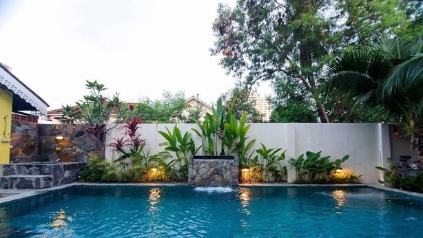 A swimming pool with a stone wall and tropical plants. - Casugria Dutch Heritage Residence (Malacca City)