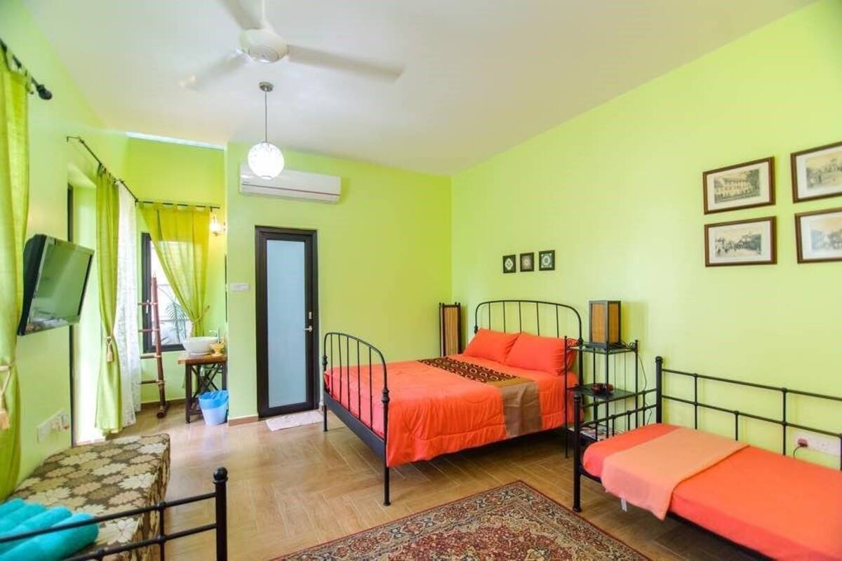 A room with two beds, a television, and a window with curtains.