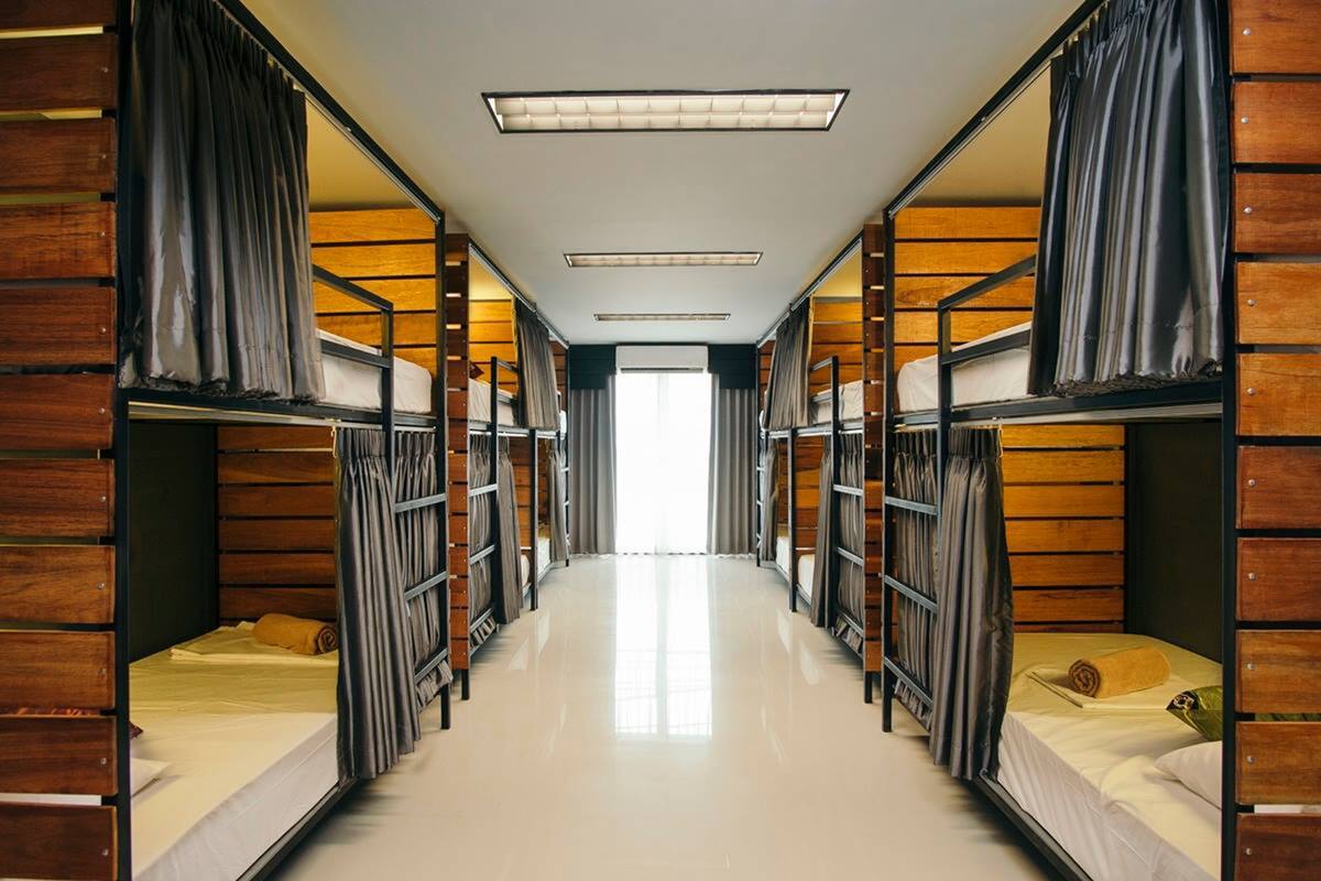 A corridor with bunk beds on either side, wooden paneling, and a bright overhead light.