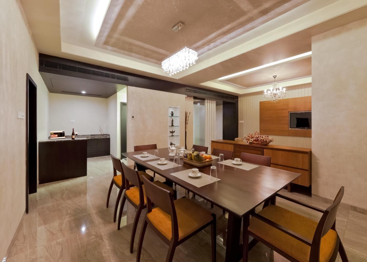 A modern dining area with a long wooden table, six chairs, and a chandelier.