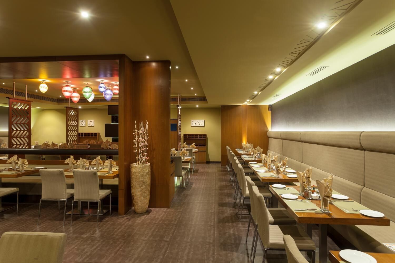 Un restaurante con mesas largas, sillas y un centro de mesa decorativo.