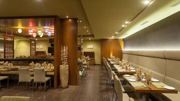 Un restaurante con mesas largas, sillas y un centro de mesa decorativo.