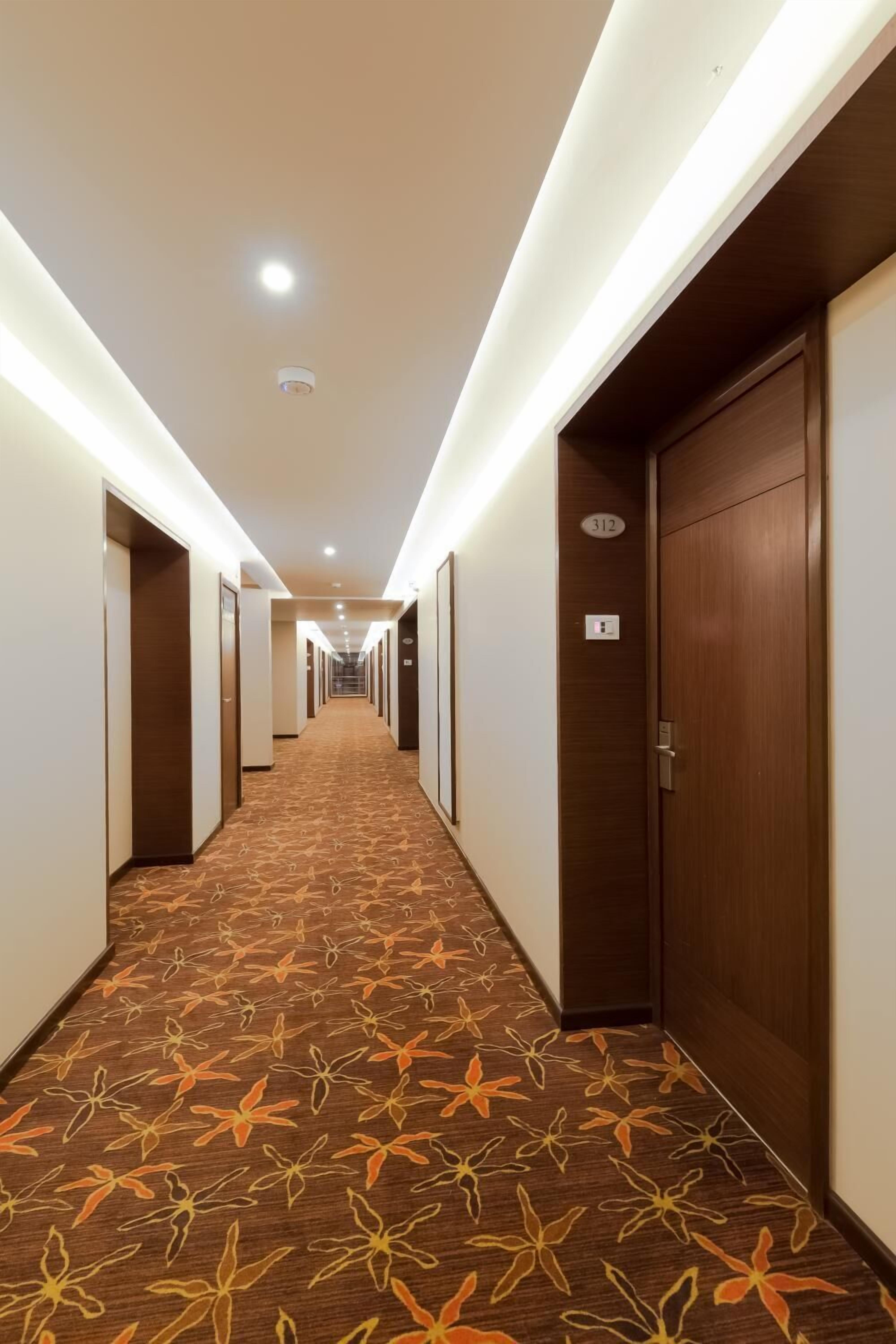 A hotel hallway with carpeted floors, wooden doors, and a number sign indicating room 312.