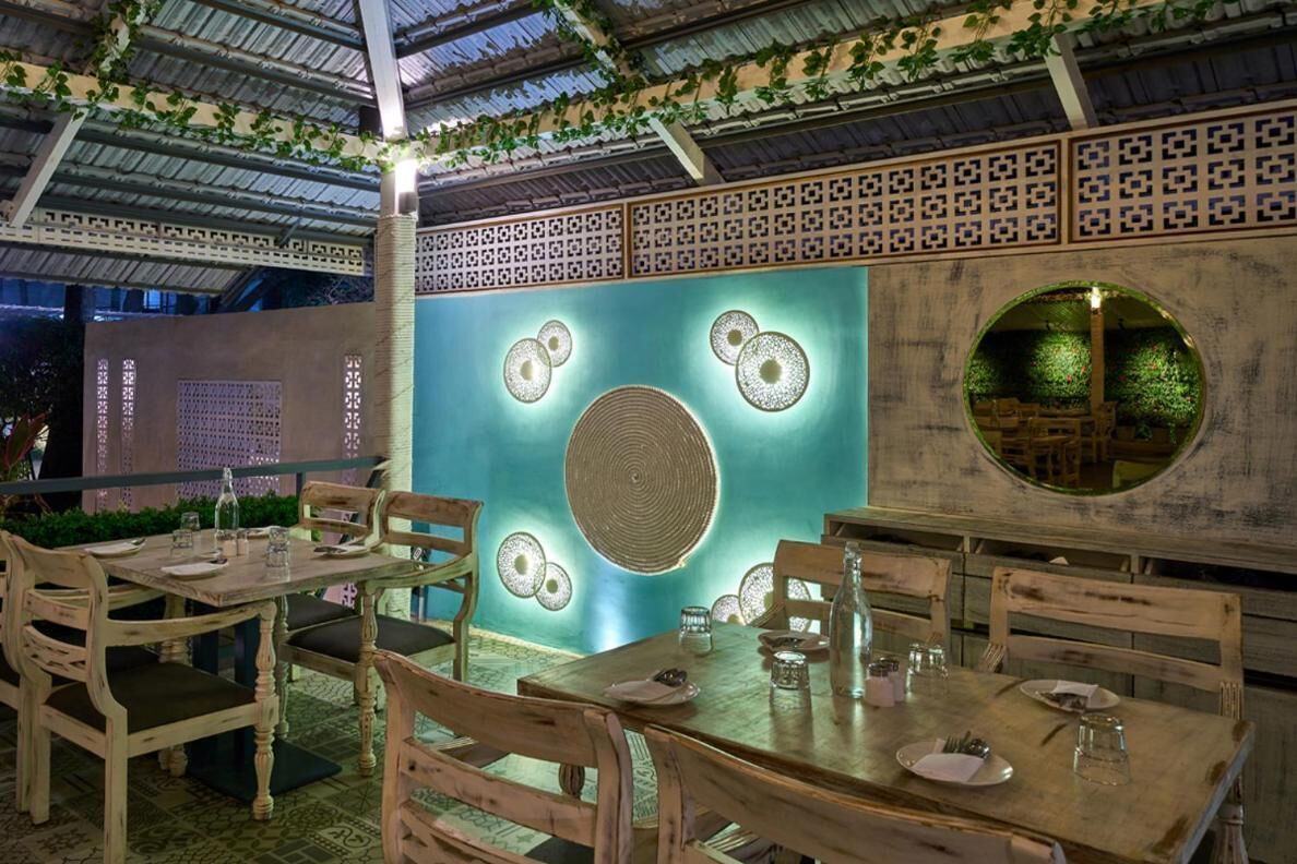 Un comedor interior con mesas y sillas de madera, paneles decorativos en la pared y un ventanal circular.