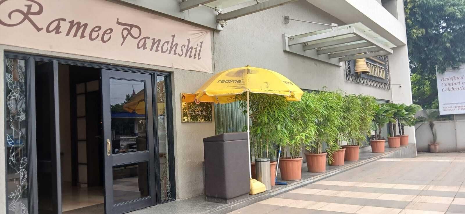 Un edificio con un letrero que dice 'Ramee Panchhil' y un paraguas amarillo.