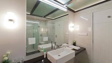 A modern bathroom with a large mirror, two sinks, and a glass-enclosed shower.