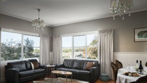 Sala de estar com sofá de couro, mesa de centro e mesa de jantar posta para uma refeição.