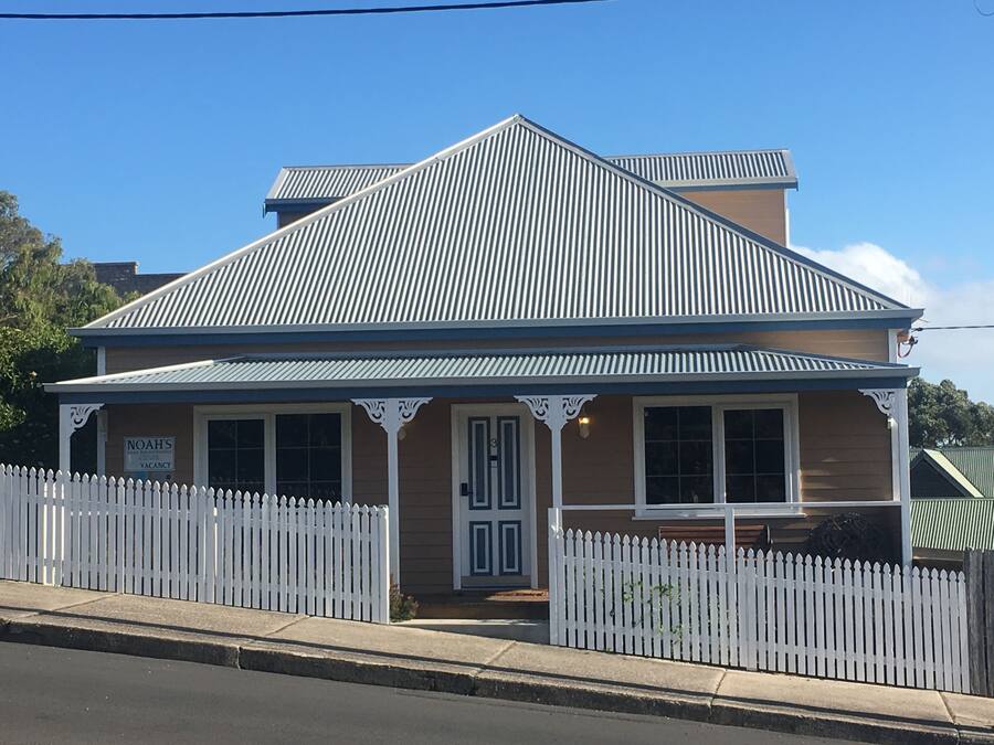 A two-story building with a metal roof and white picket fence.