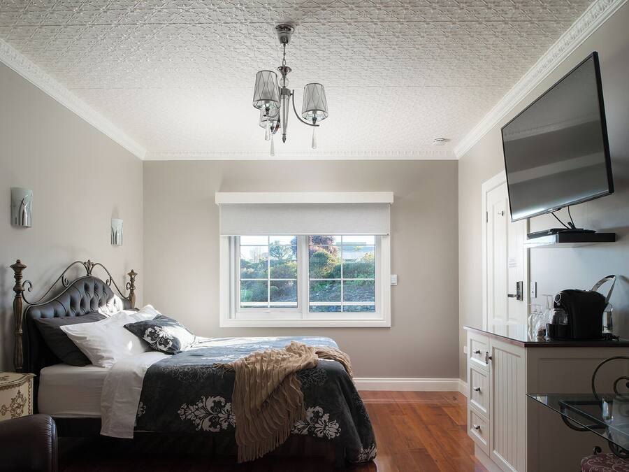 Un dormitorio con cama, ventana, televisor y armario.