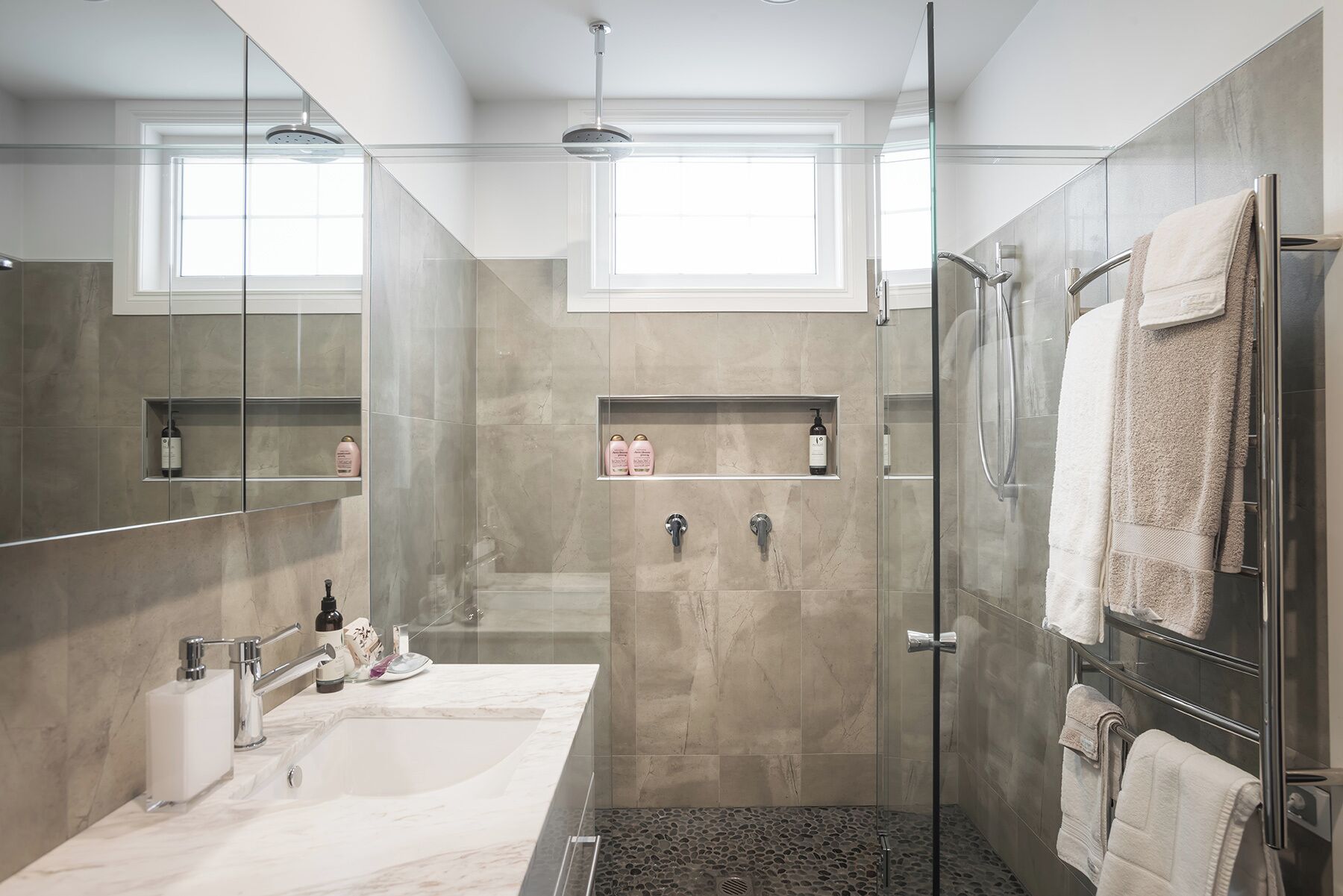 Un bagno moderno con box doccia in vetro, uno specchio grande e un mobile lavabo.