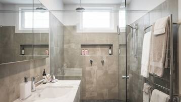 Un bagno moderno con box doccia in vetro, uno specchio grande e un mobile lavabo.